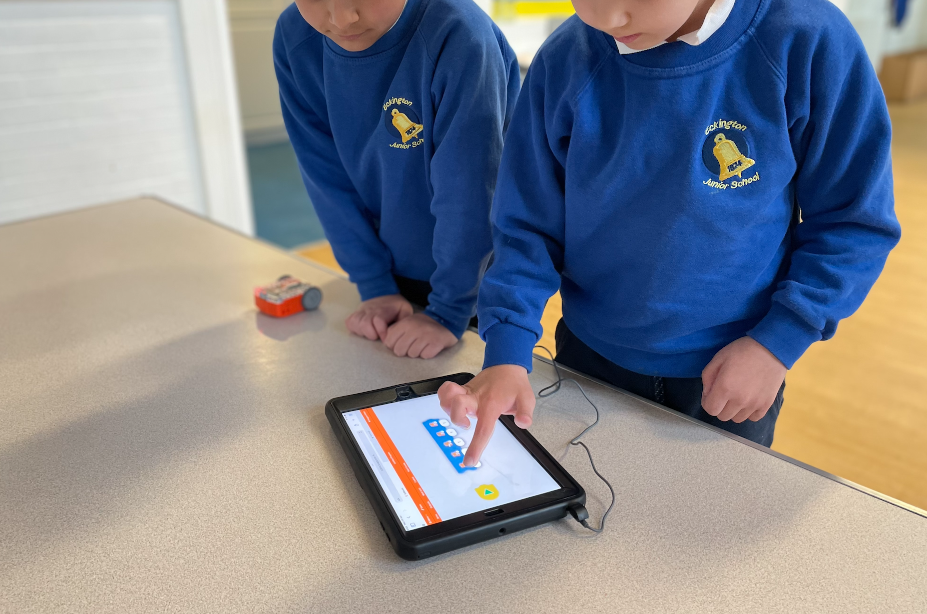 two children at after school club using edison robot with an ipad