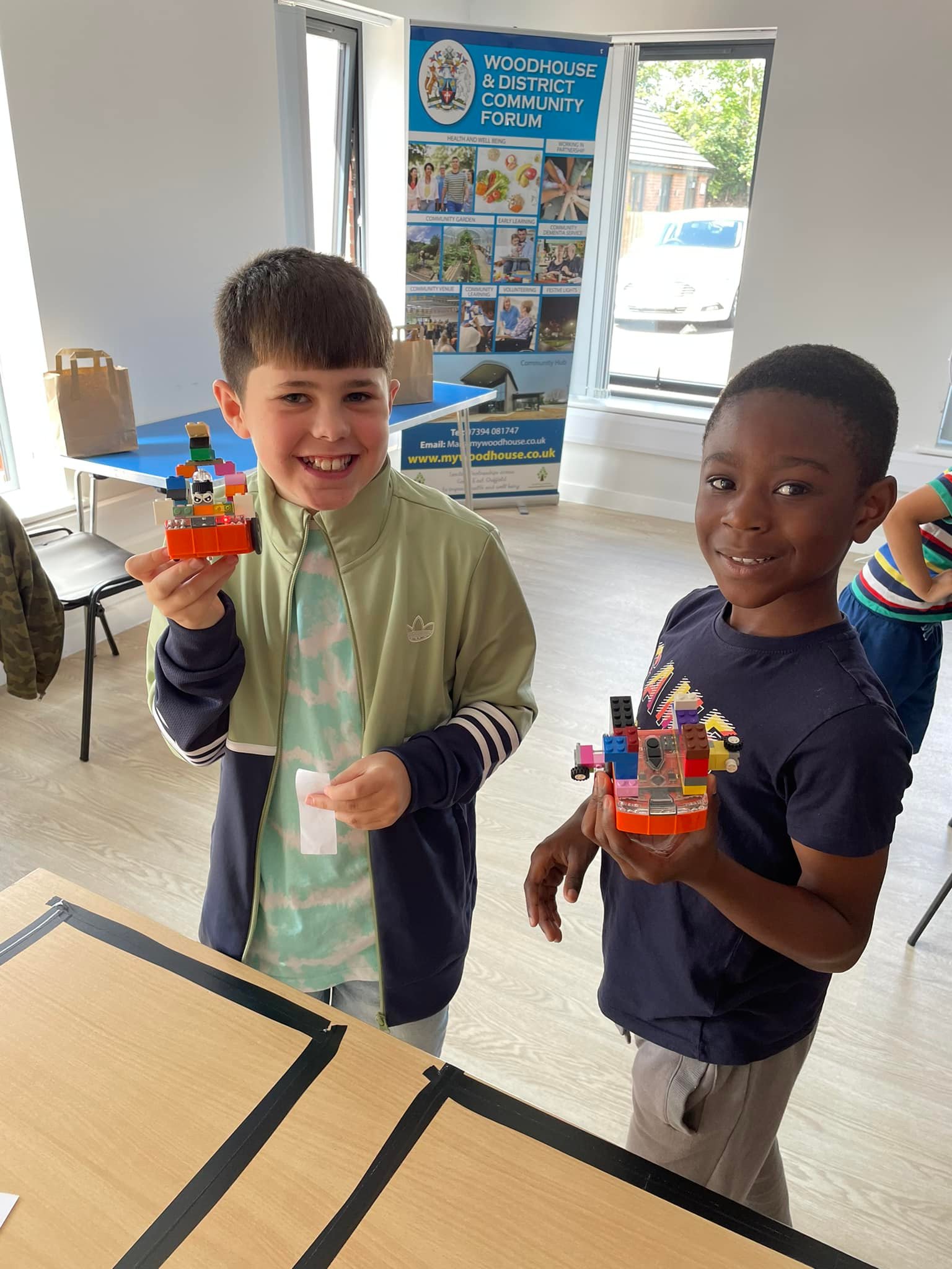 two children holding an edison robot built with lego ready to sumo battle